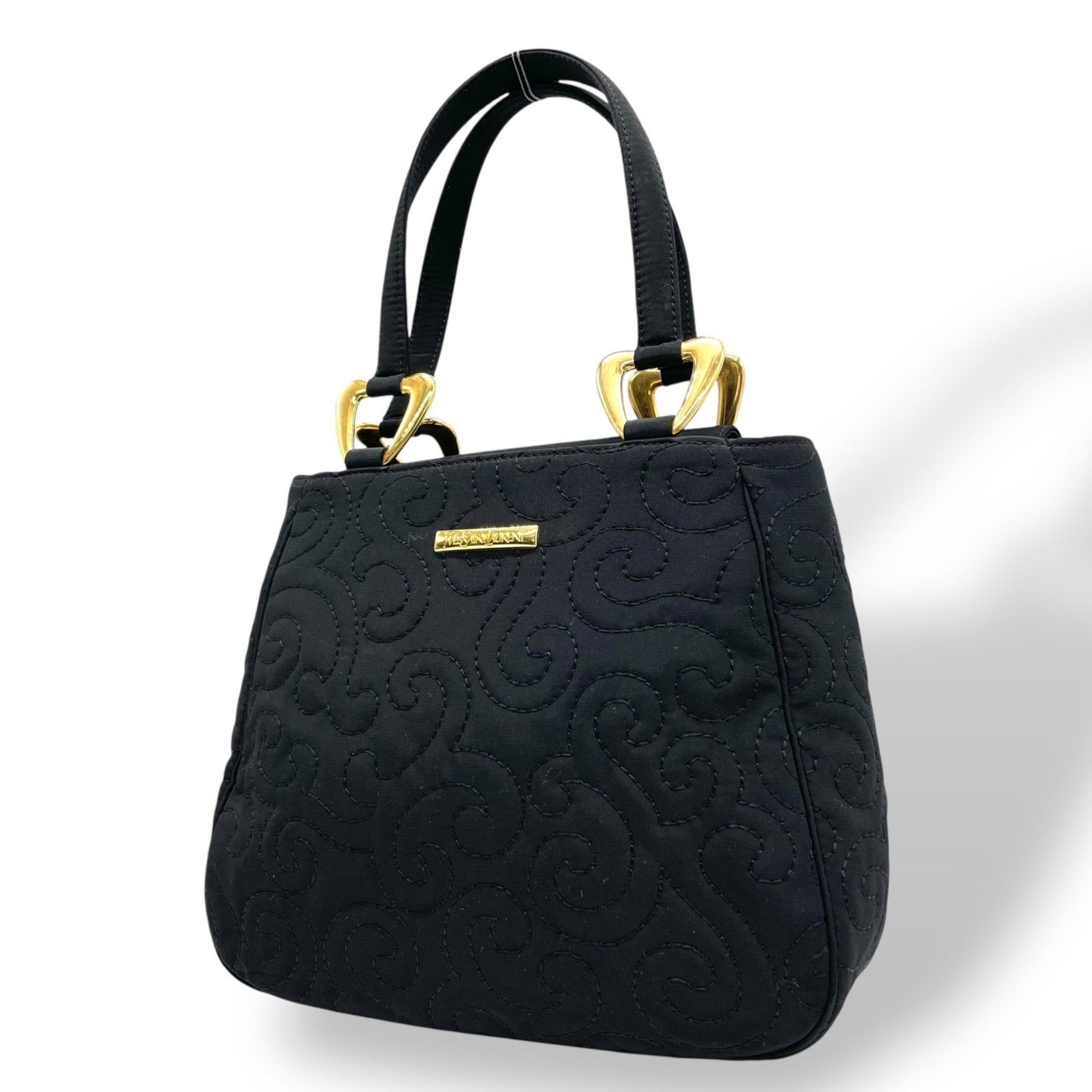 Yves Saint Laurent handbag in with gold hardware and a quilted swirl pattern.
